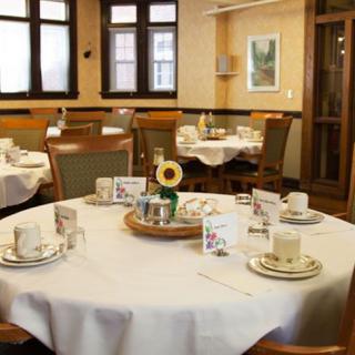 A cozy dining room with neatly set tables, featuring white tablecloths and decorative centerpieces.