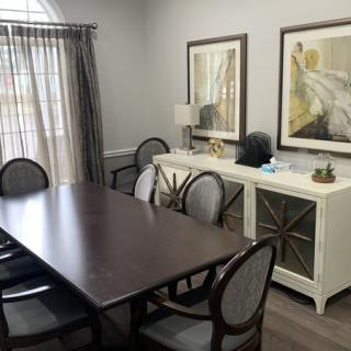 A stylish dining room with a dark wooden table, upholstered chairs, and elegant artwork on the wall.