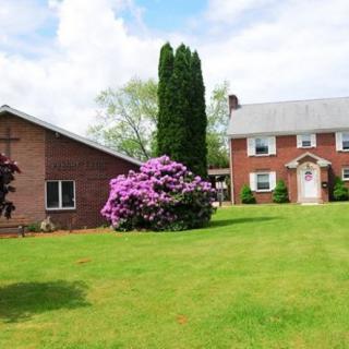 A brick house with a spacious lawn and blooming bushes.