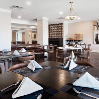 A modern restaurant dining area with neatly arranged tables and chairs, featuring folded napkins on each table.