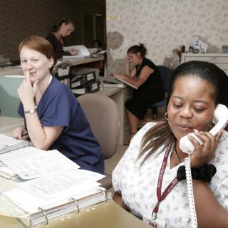 Office workers handling tasks at their desks, with one on the phone.