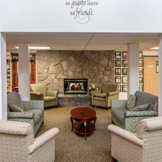 A cozy living room with a stone fireplace, surrounded by comfortable armchairs and a central wooden table.