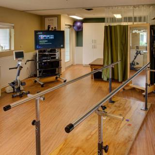 A rehabilitation room equipped with parallel bars and exercise equipment.
