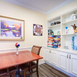 A cozy dining room featuring a wooden table, chairs, built-in shelves, and decorative items.