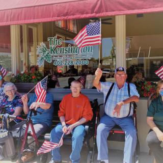 A group of elderly individuals sitting outdoors, holding American flags in a display of patriotism.