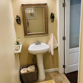 A small, well-decorated bathroom featuring a pedestal sink and framed mirror.