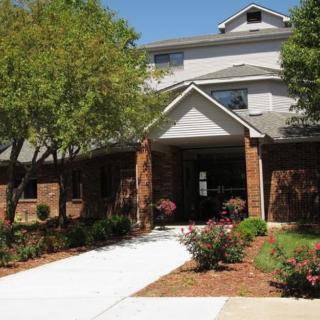 A two-story residential building with a landscaped entrance and trees.