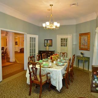 A traditional dining room with an elegantly set table and a chandelier overhead.