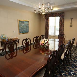 A traditional dining room with a long table, elegant chairs, and a chandelier.