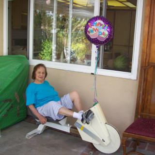A person relaxing on a stationary exercise bike outside, next to a festive balloon.