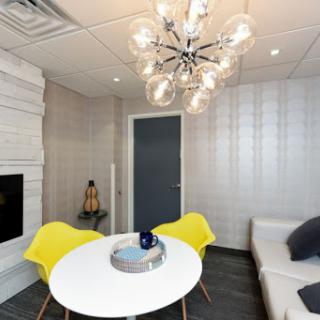 A stylish modern living space featuring a round table, yellow chairs, and a contemporary chandelier.