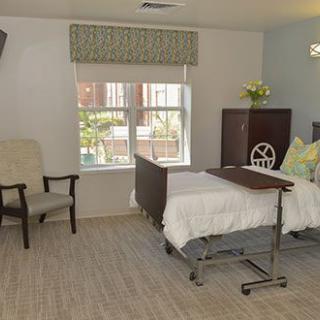 A clean and organized hospital room with a medical bed and seating area.