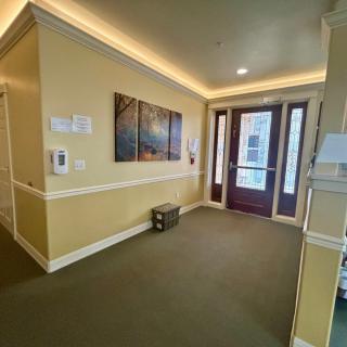 A well-lit hallway with artwork on the wall, leading to a glass door entrance.
