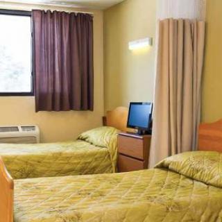 A cozy bedroom with twin beds and a computer on a wooden desk.