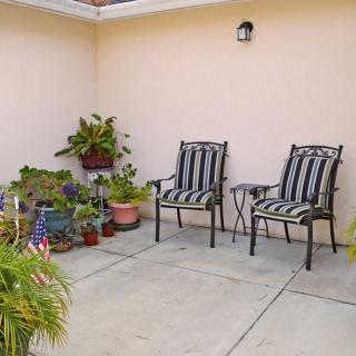A cozy patio area with two striped chairs surrounded by potted plants.