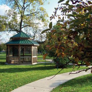 A peaceful park scene featuring a gazebo surrounded by trees and a winding pathway.