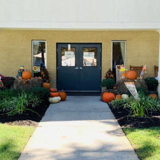 A welcoming entrance adorned with colorful pumpkins and vibrant flowers, capturing the essence of autumn.