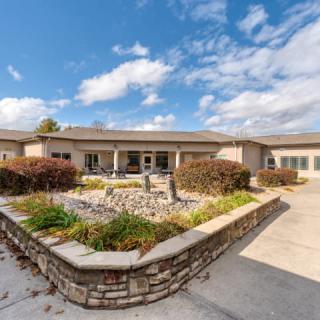 A spacious single-story house with well-maintained landscaping under a bright blue sky.