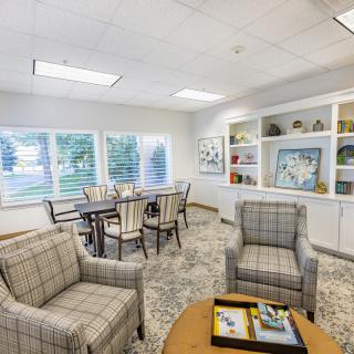 A cozy indoor seating area with plaid chairs, a round table, and decorative shelves.