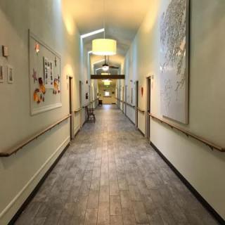 A well-lit hallway with artwork on the walls and a tiled floor.
