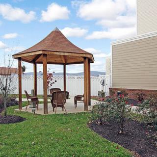 A cozy outdoor gazebo with seating surrounded by a well-maintained lawn and landscaping.