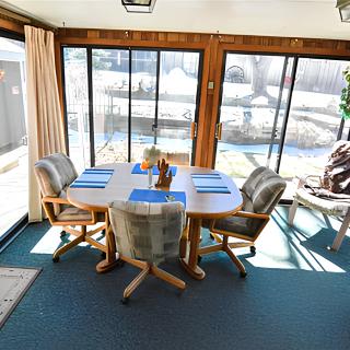 A bright dining area with a table and chairs, surrounded by large windows offering a scenic view.