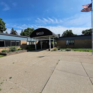 A sunny day at the entrance of a building with an American flag.