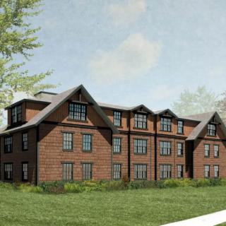 A three-story residential building with a brick facade and surrounding greenery.