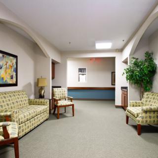 A cozy waiting room with sofas, artwork, and a potted plant.