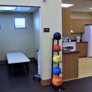 A therapy room within a clinic featuring exercise equipment and a treatment bed.