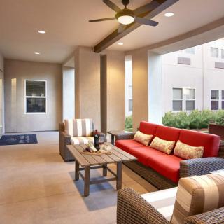 A modern outdoor patio with comfortable seating and a ceiling fan.