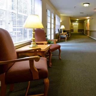 A well-lit hallway with chairs and end tables along one side.