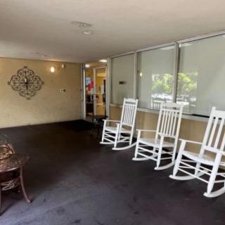 A cozy outdoor seating area with white rocking chairs lined up on a porch.