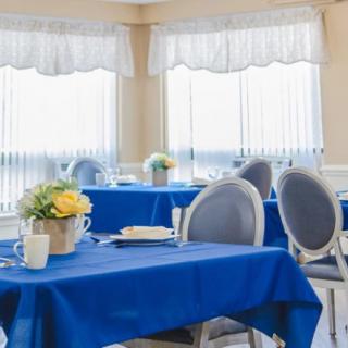 A bright dining area with blue tablecloths and floral centerpieces.
