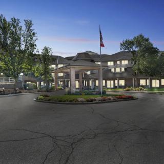 A well-lit building with a driveway and flagpole at night.