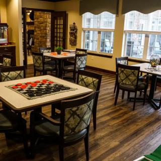 An empty dining area with several tables and chairs, featuring a checkered board game on one table.