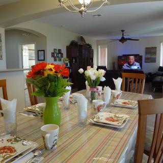 A well-set dining table with colorful flowers and neatly arranged dinnerware in a cozy home interior.