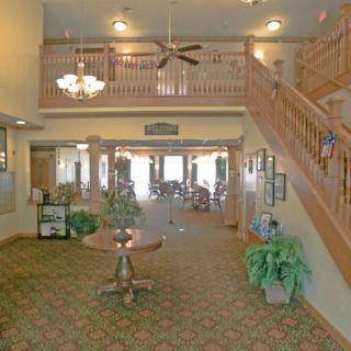 A spacious and elegant lobby featuring a grand staircase, chandelier, and comfortable seating.