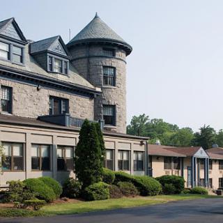 An elegant hotel featuring a turret and manicured landscaping.