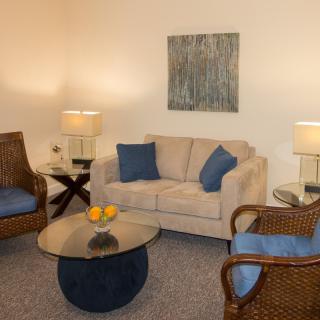 A cozy living room with a beige sofa, matching wicker chairs, and a round coffee table.