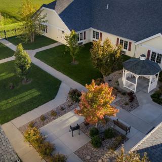 An aerial view of a house with landscaped gardens and a gazebo during autumn.