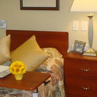 A cozy bedroom with a nightstand, table lamp, and decorative pillows.