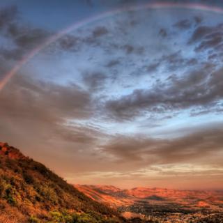 A stunning sunset view showcasing a vibrant rainbow over the mountains.