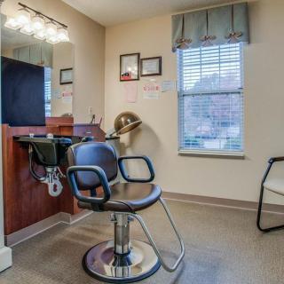A cozy salon space with a barber chair, mirror, and hair dryer beside a window.