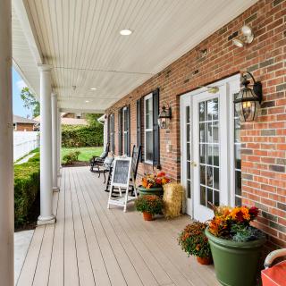 A cozy porch with brick walls, decorated with plants and flowers.