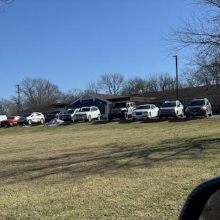 A view of a building surrounded by parked vehicles on a sunny day.