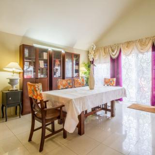 A well-lit dining room with a table, chairs, and a cabinet, featuring elegant decor and curtains.
