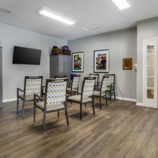 A modern waiting room with arranged chairs, a television on the wall, and decorative artwork.
