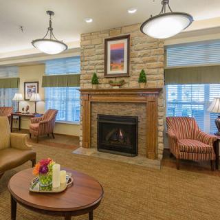 A cozy living room with a stone fireplace, comfortable armchairs, and a coffee table adorned with decorative items.