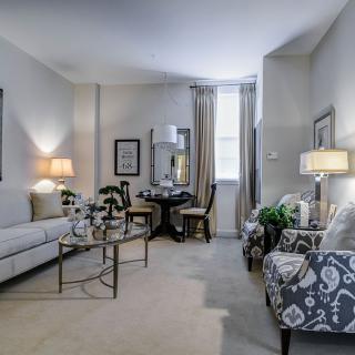 A cozy and elegantly decorated living room featuring a comfortable sofa, patterned armchairs, and stylish lighting.